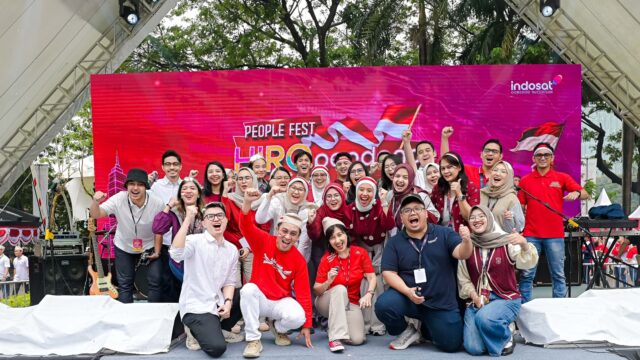 Karyawan Indosat Ooredoo Hutchison berpose bersama dalam acara People Fest HUT RI dengan latar panggung merah bertema kemerdekaan.